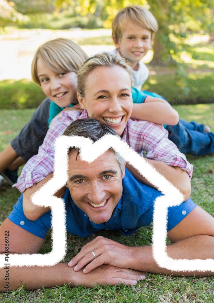 Happy family lying in park overlaid with house shape