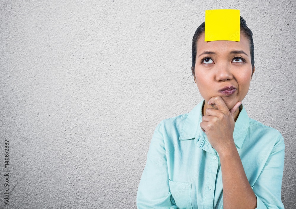 Thoughtful woman with sticky note on her forehead