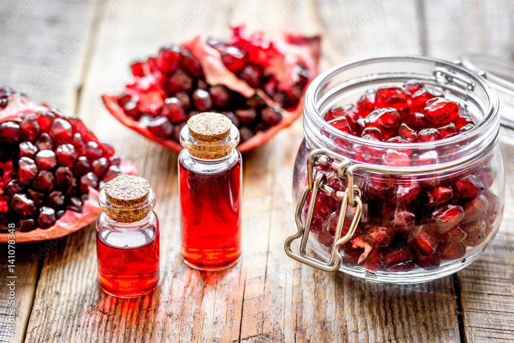 sliced pomegranate and extract in glass on wooden background