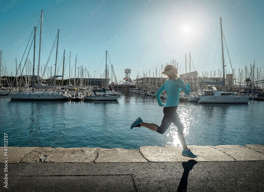 Woman running on the coastline under sunlight.