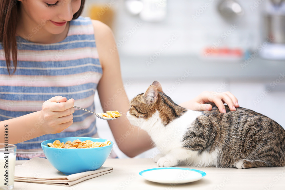 Morning of beautiful young woman and cat in kitchen