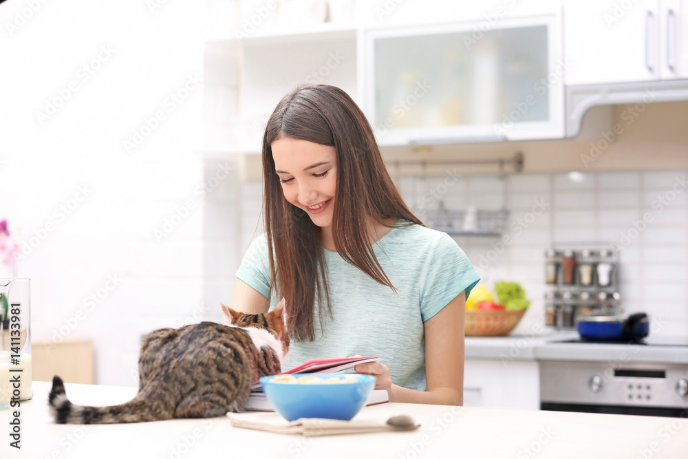 Morning of beautiful young woman and cat in kitchen