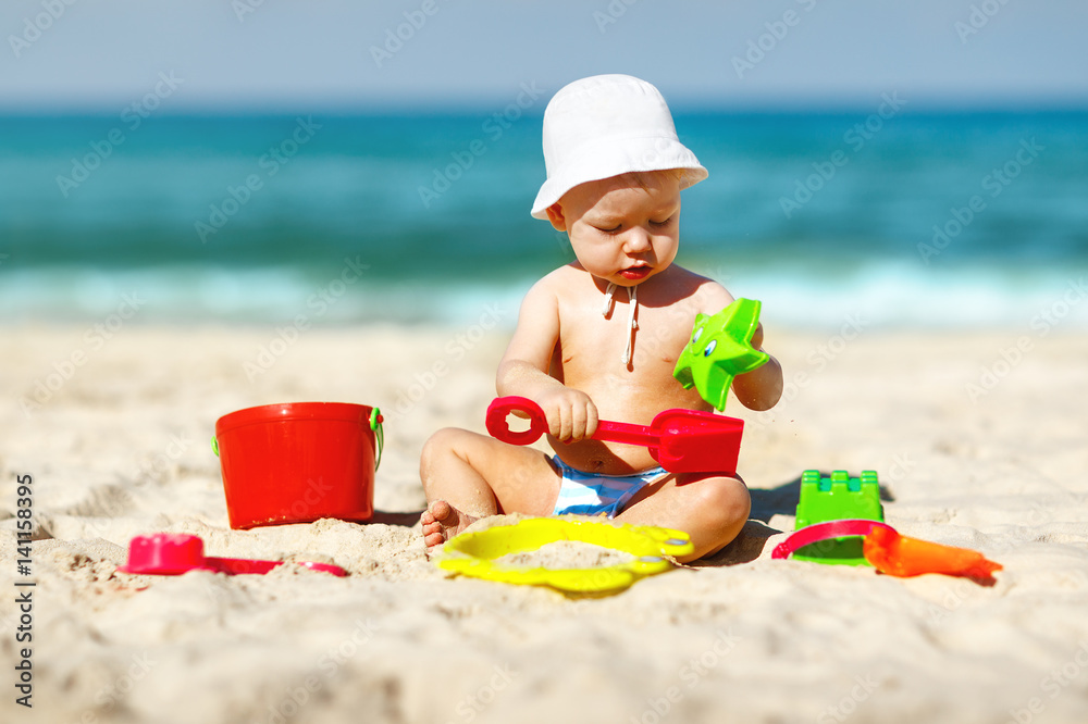 baby boy playing with toys and sand on beach