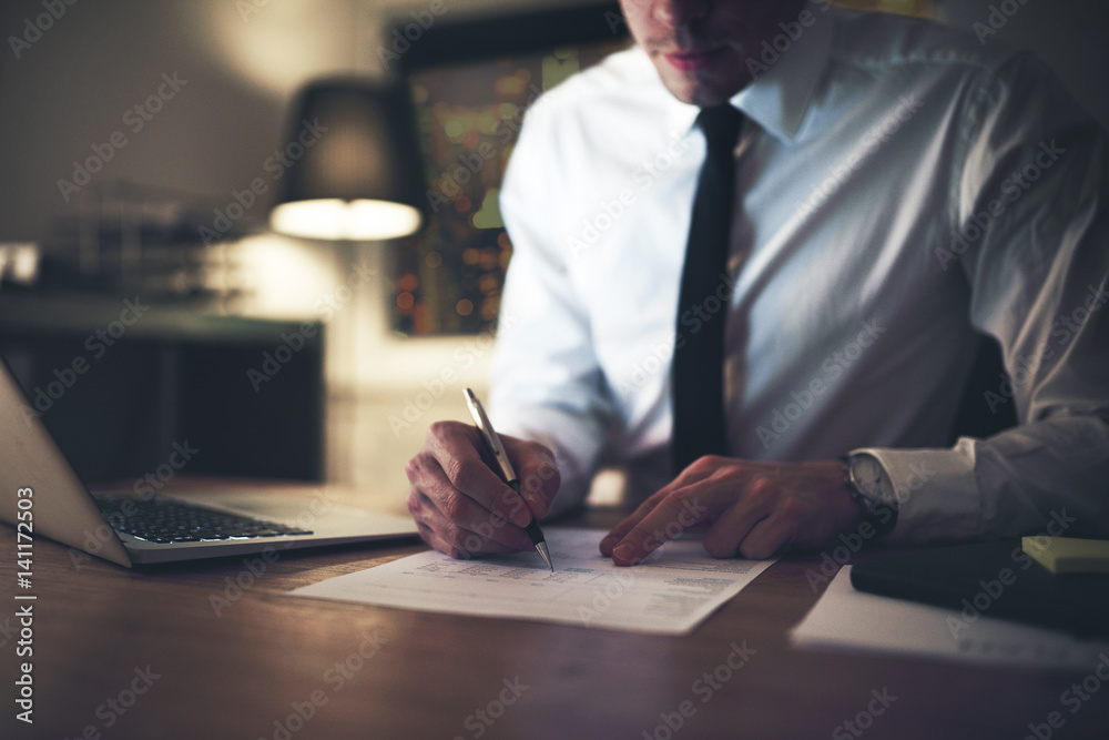 Serious businessman signing contract at office