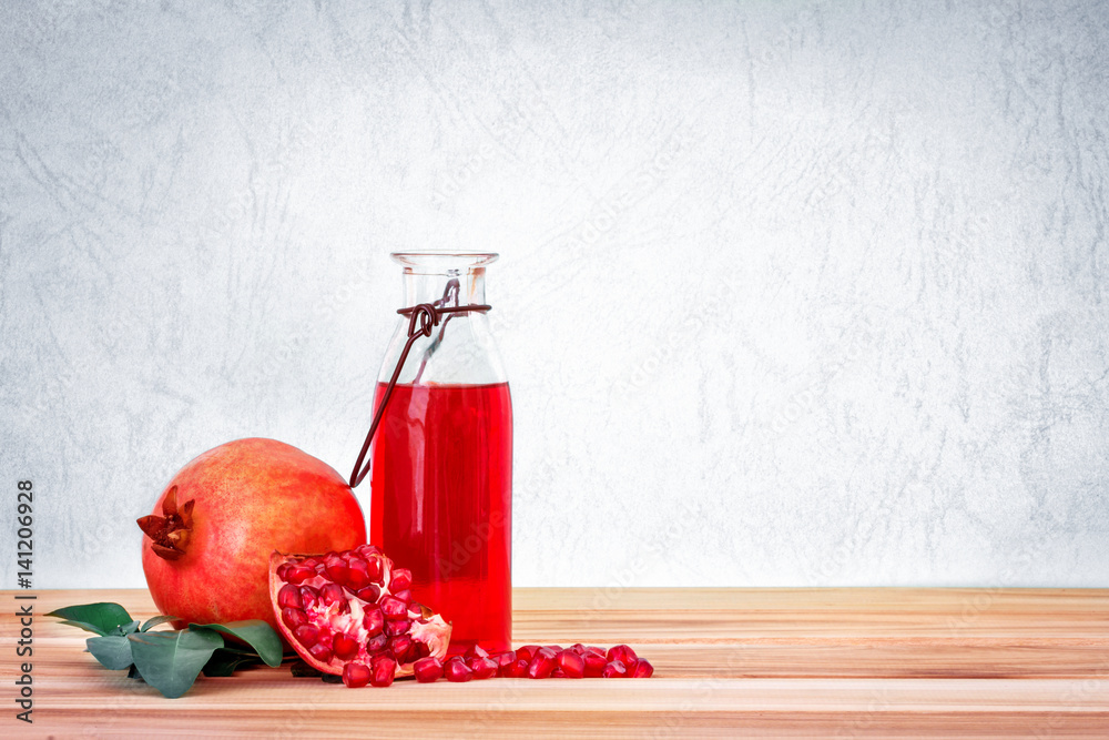 fresh red pomegranate juice with pomegranate seed and fruit with leaf on wooden table and blue backg