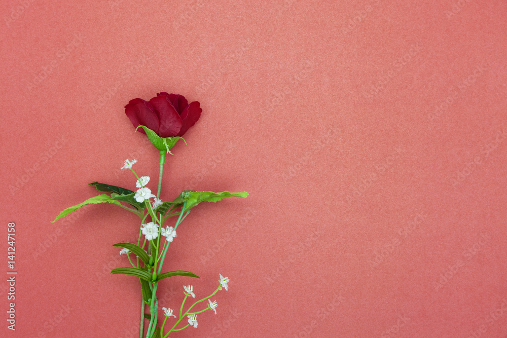 plastic rose flower on red paper background.