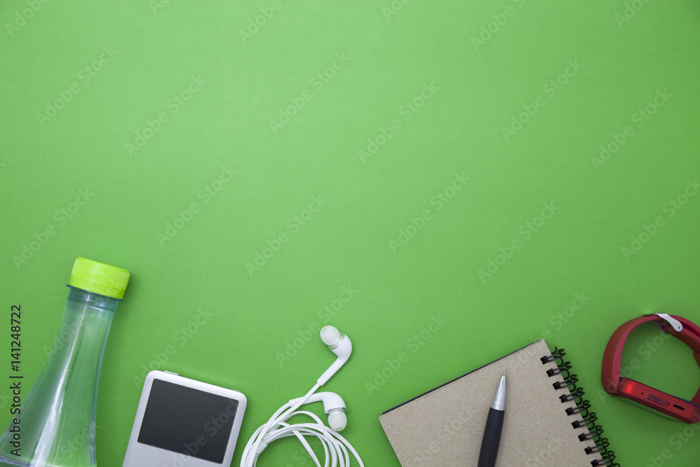 close up of water bottle,music player,watch,paper note,pen  and earphones on green background,fitnes