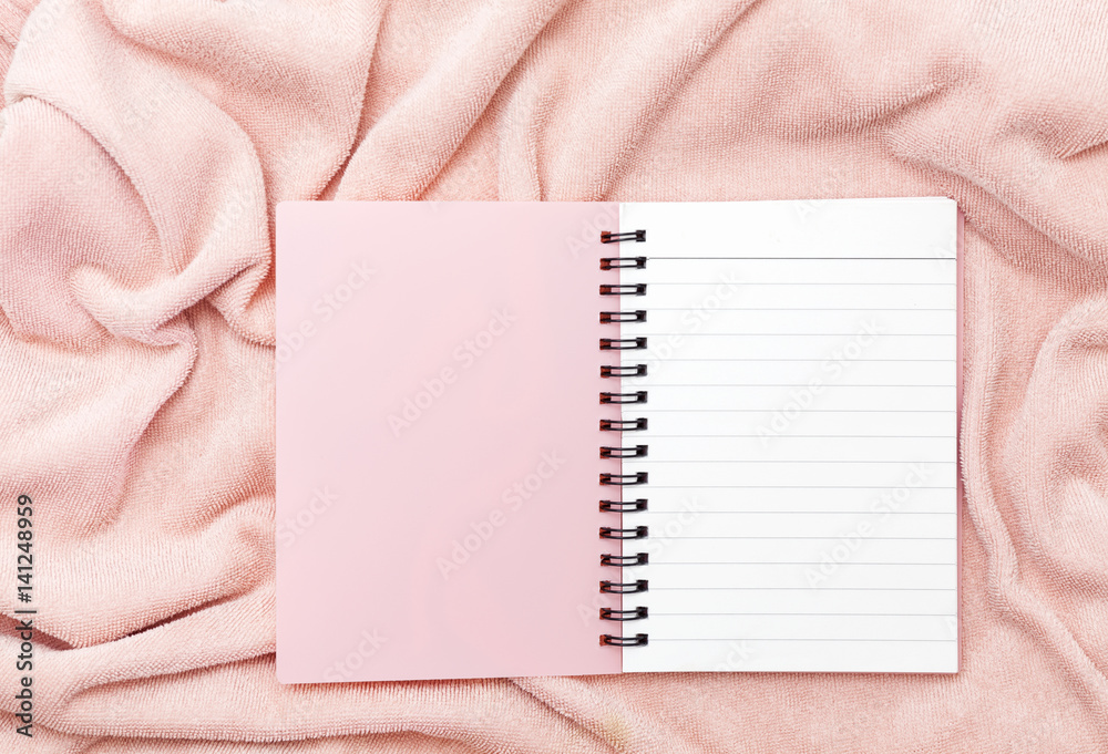 pink paper notebook on pink towel cloth background.