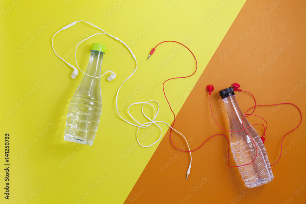 close up of water bottle and earphones on beautiful retro pastel color paper background,fitness back