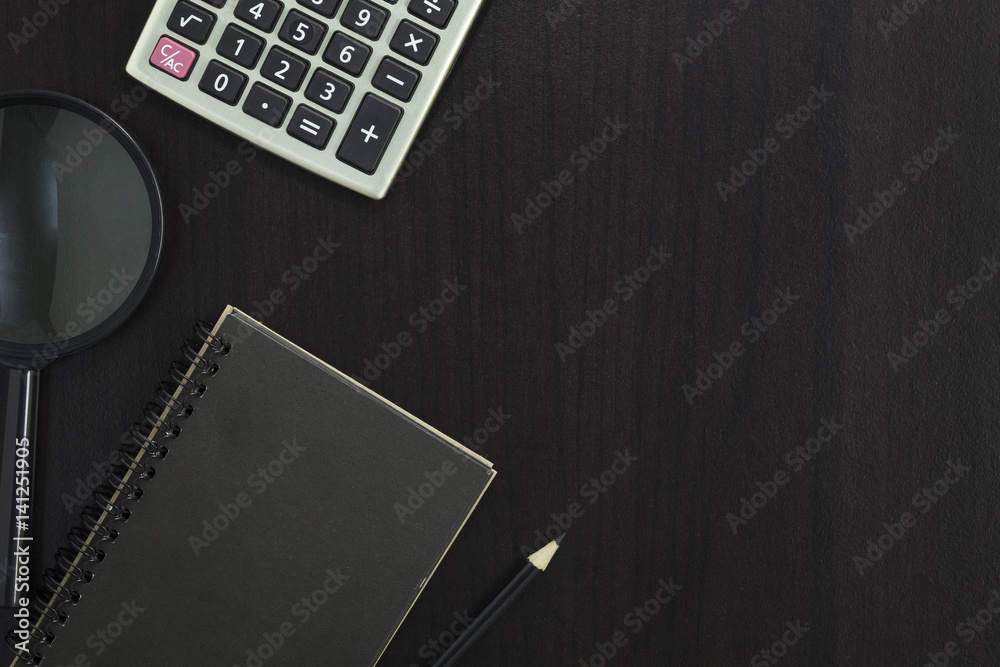 notebook with pencil , calculator,magnifier on dark wood background.