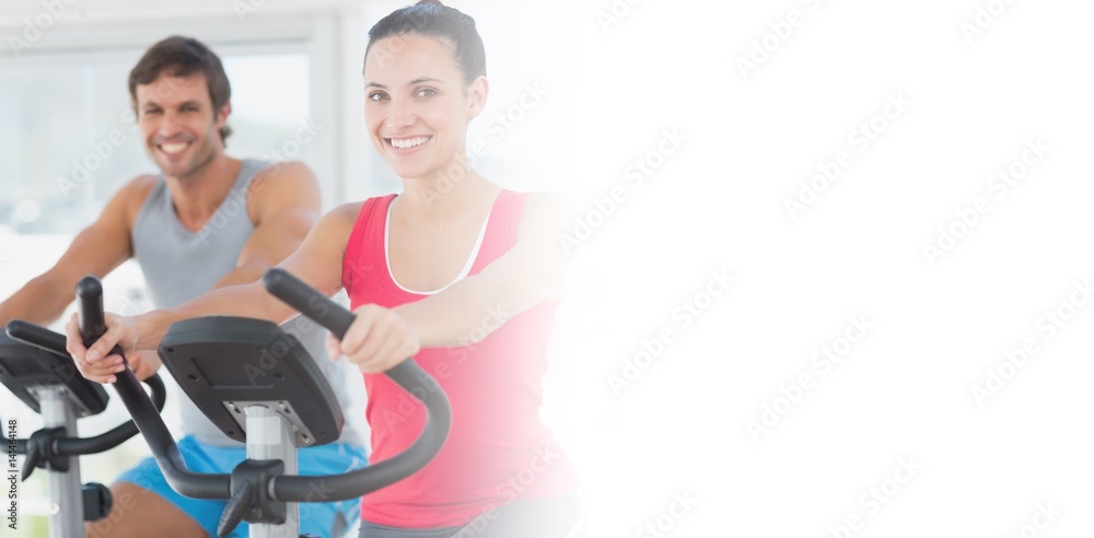 Smiling young couple working out at spinning class