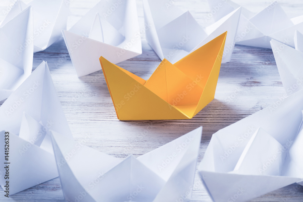 Business leadership concept with white and color paper boats on 