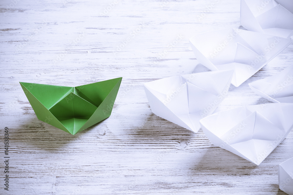 Business leadership concept with white and color paper boats on 