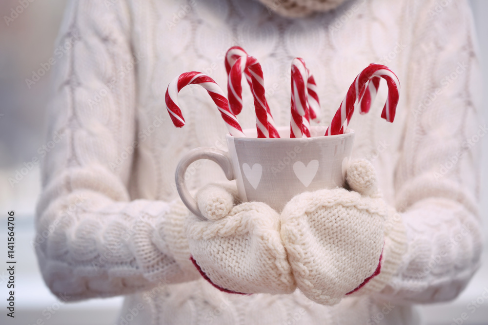 Woman holding cup with candy canes, closeup