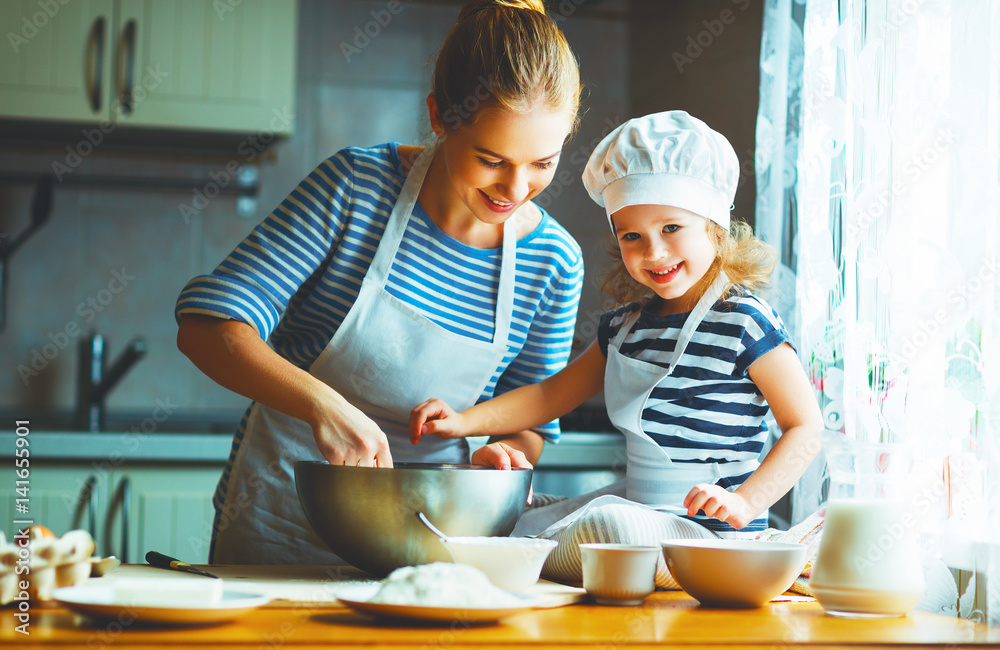 happy family in kitchen. mother and child preparing dough, bake cookies