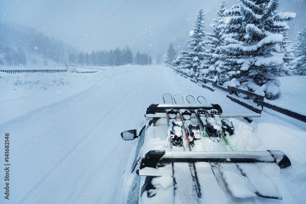 Ski trip with skis on the car roof during snowfall