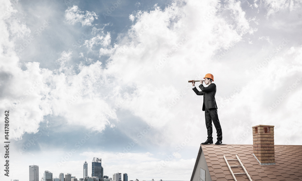 Engineer man standing on roof and looking in spyglass. Mixed med