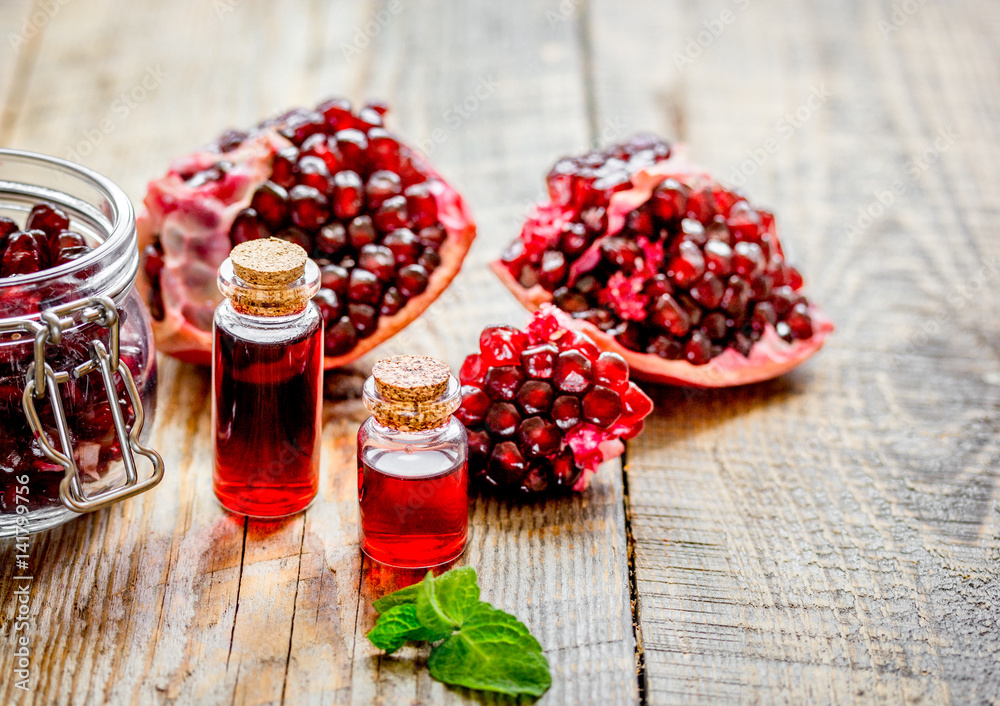 sliced pomegranate and extract in glass on wooden background