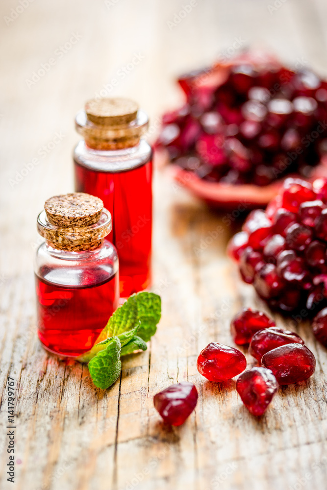 sliced pomegranate and extract in glass on wooden background