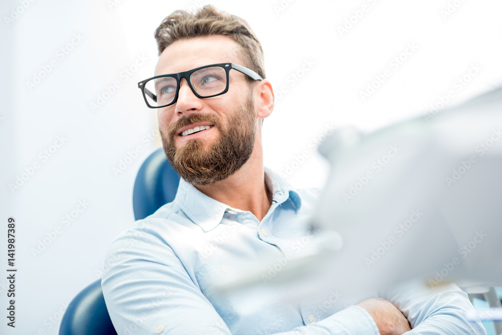 Handsome businessman with great smile sitting on the dental chair