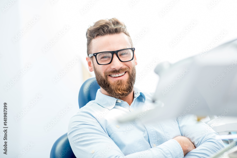 Handsome businessman with great smile sitting on the dental chair