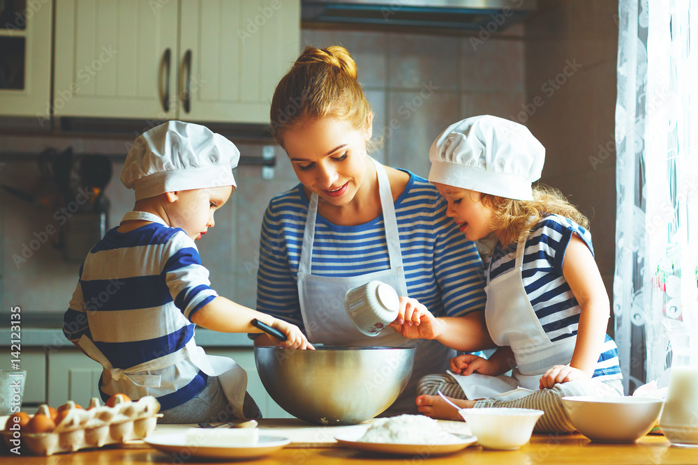 happy family in kitchen. mother and children preparing dough, bake cookies