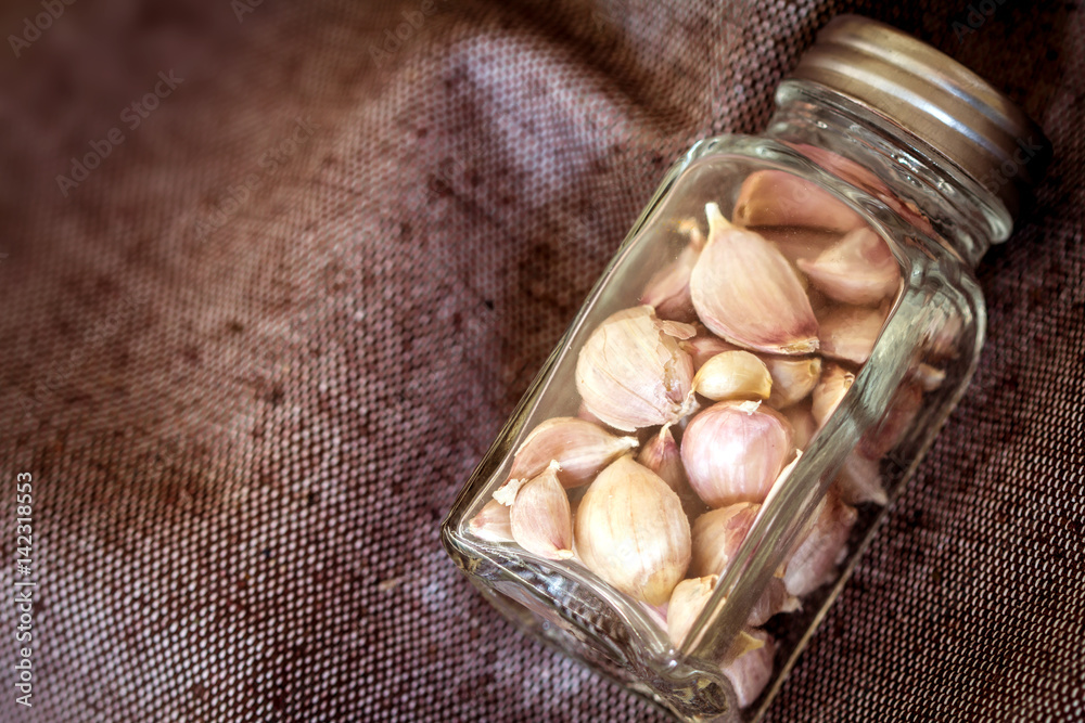 Close up garlic in glass battle on brown fabric