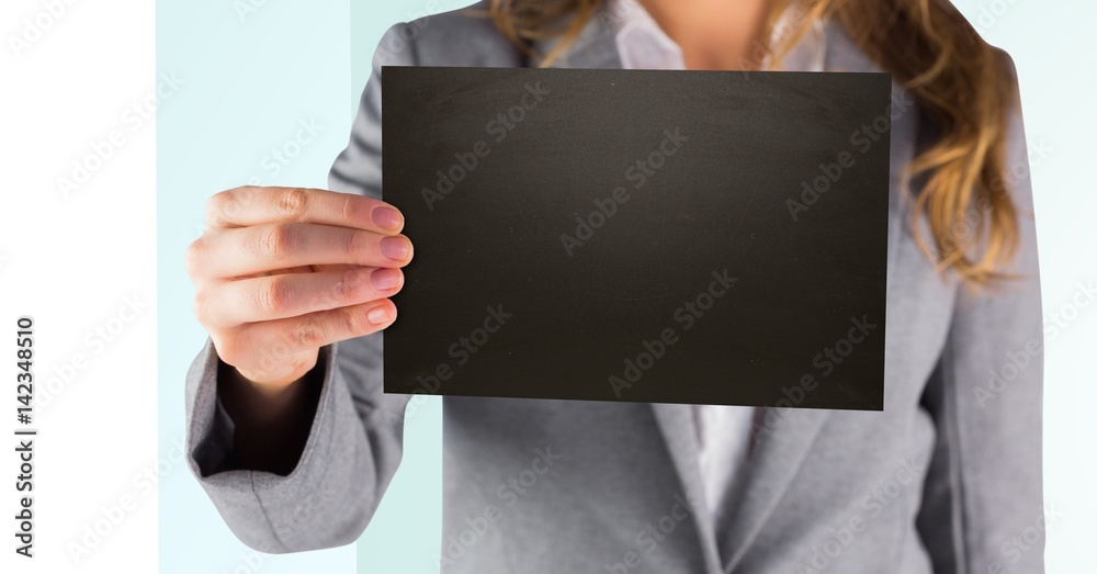 Business woman holding out black blank card against white and green background