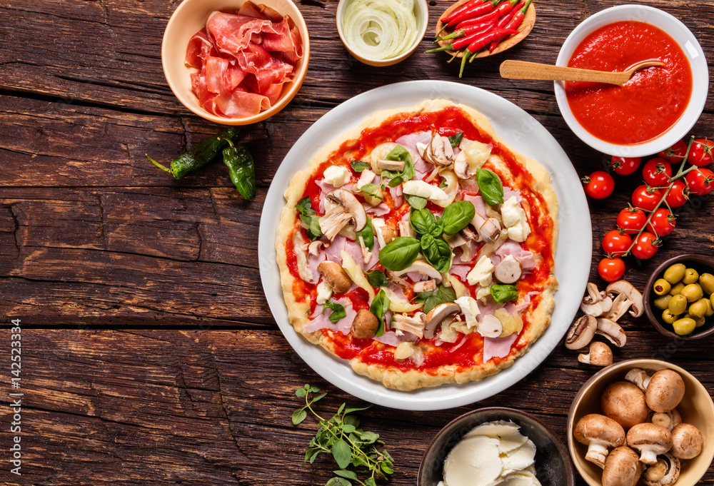 Pizza dough with ingredients on wood