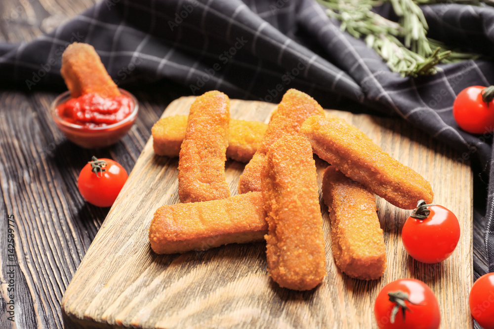 Board with cheese sticks and ketchup sauce on wooden background