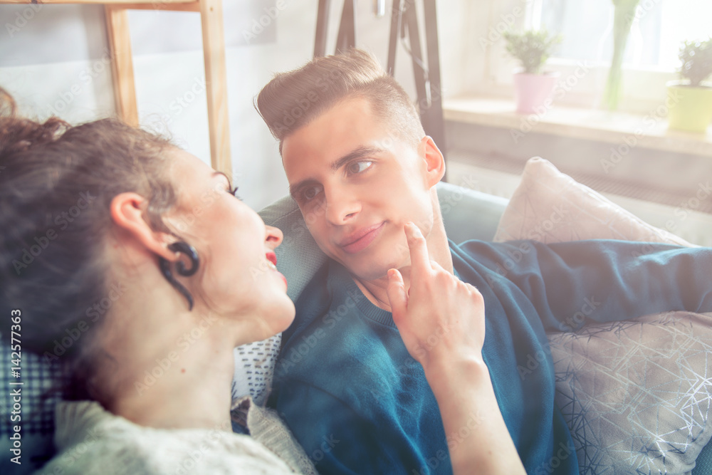 Loving couple relaxing on sofa looking at each other home interior