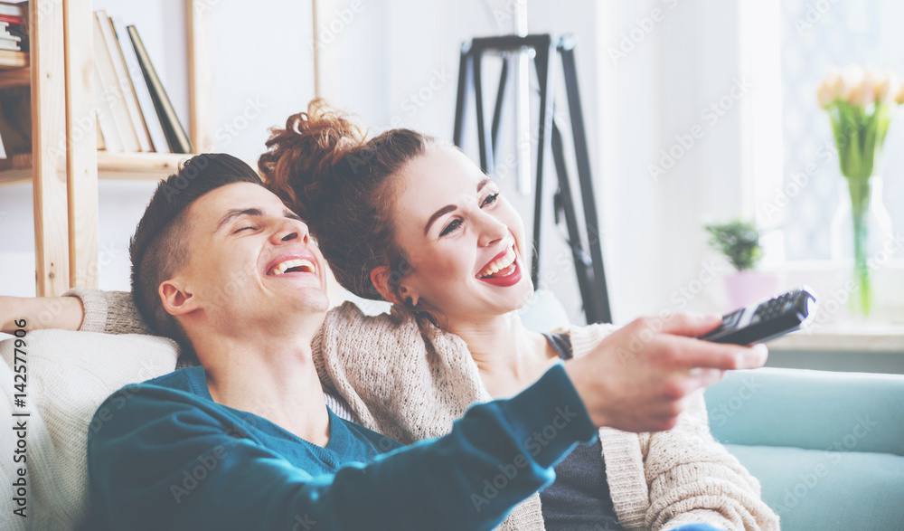 Loving couple on sofa at home watching tv and laughing