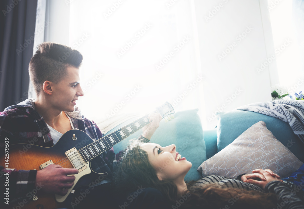 Couple playing the guitar and singing on sofa at home