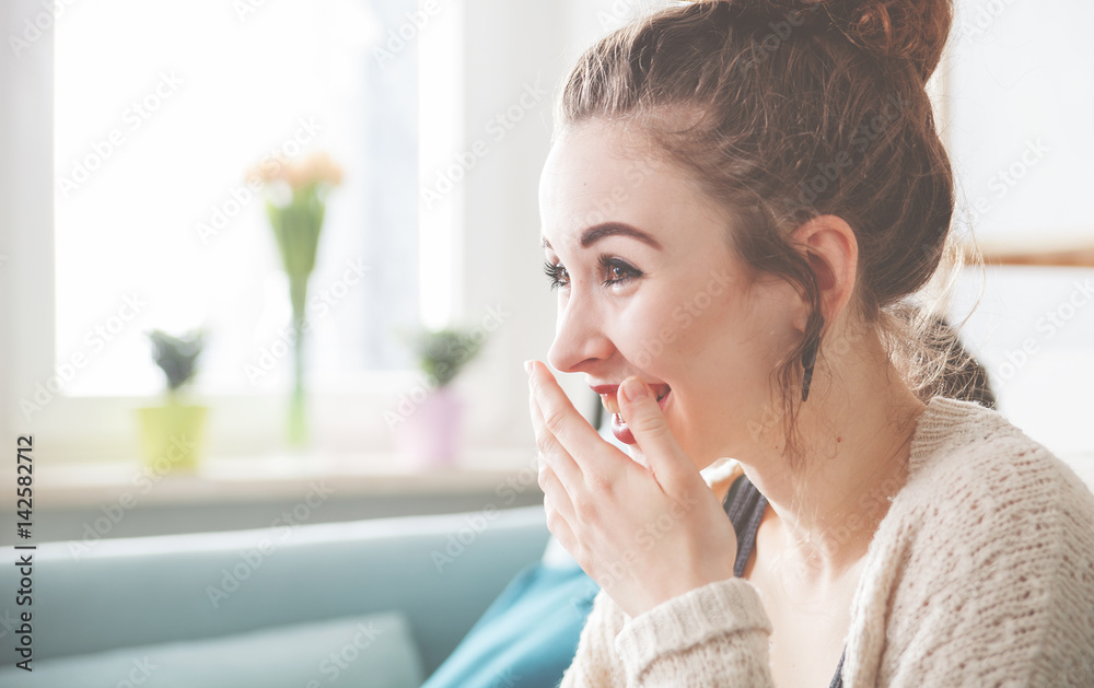 Beautiful woman at home laughing while watching something