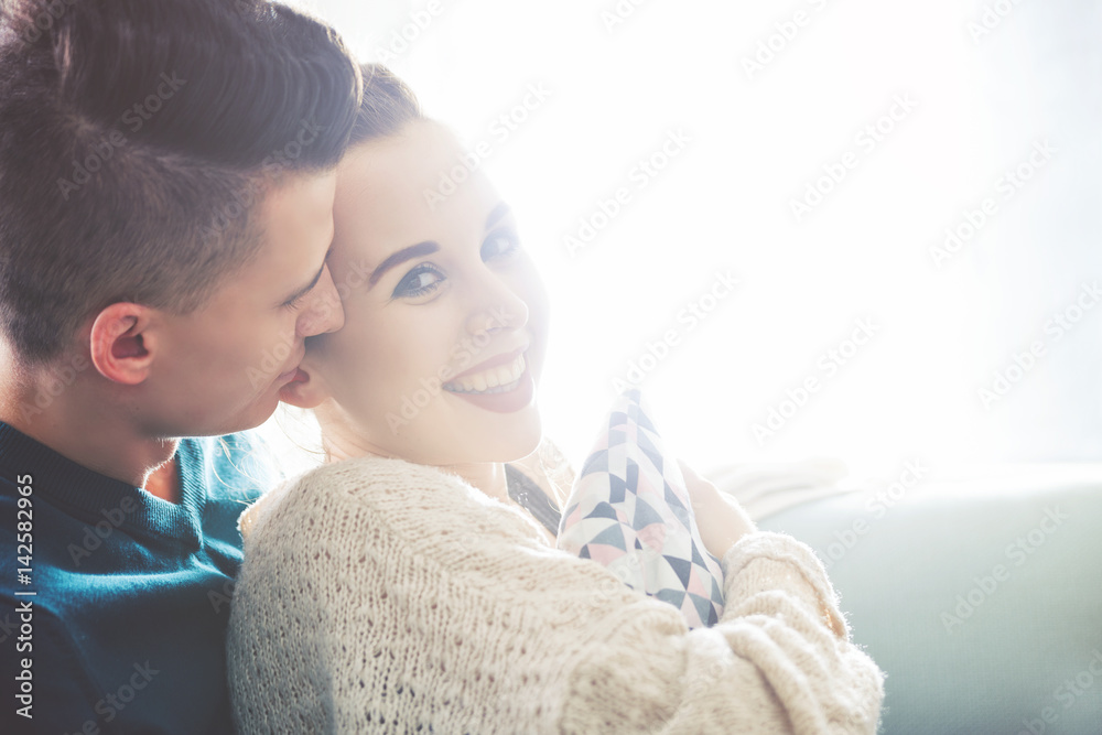 Loving young couple hugging and lying on sofa at home