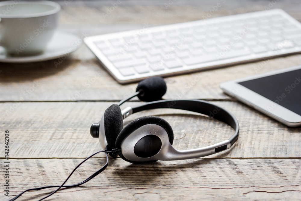 Office desk with headset and keyboard wooden background