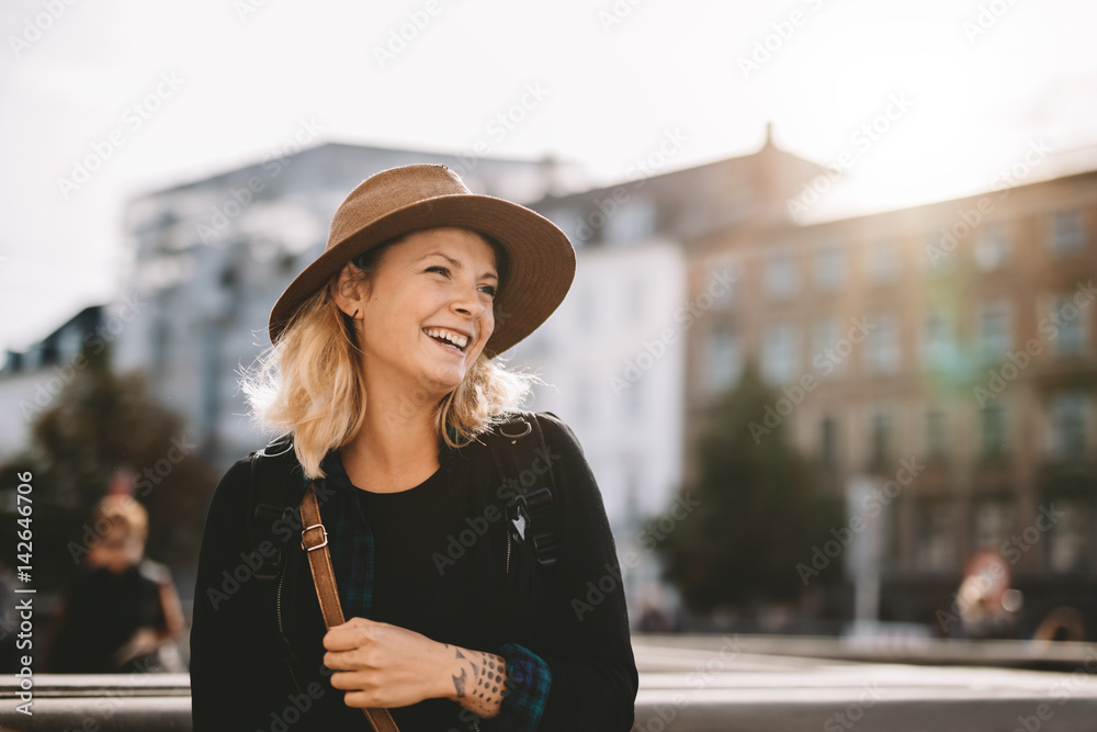 戴着帽子微笑的旅游妇女。