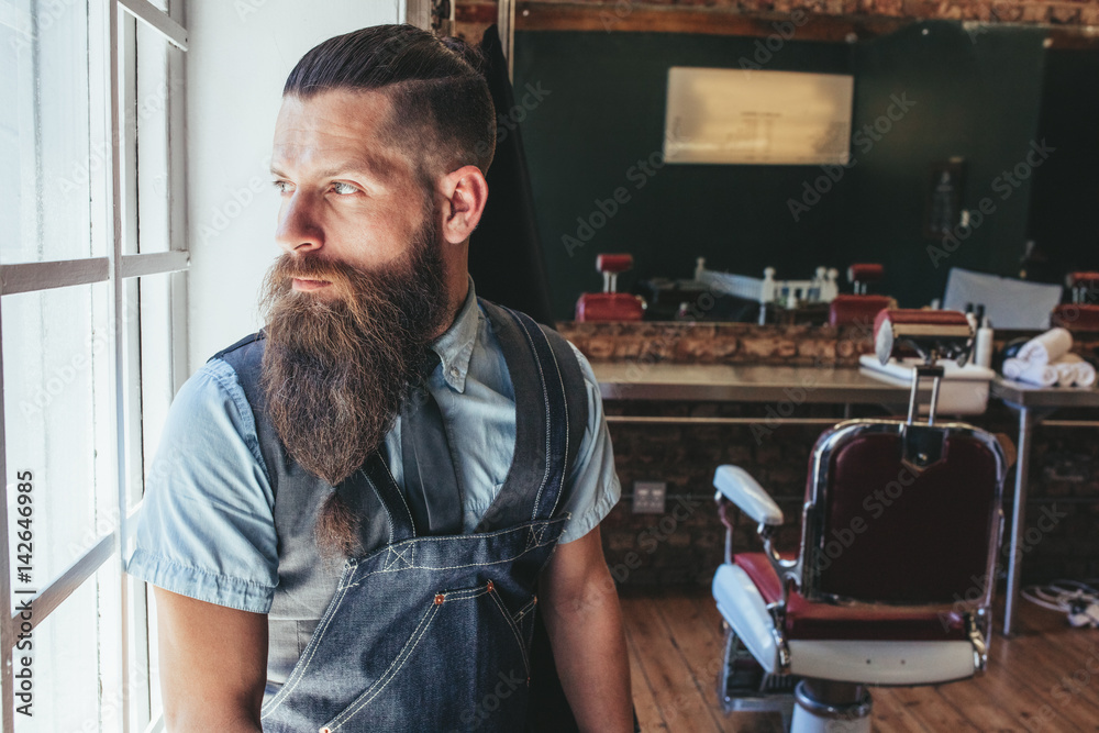 Barber standing by window and looking away