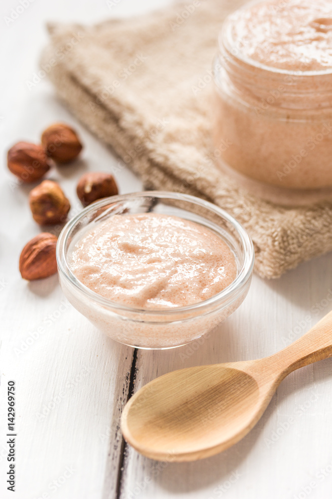 cosmetic set with hazelnut scrub on table background