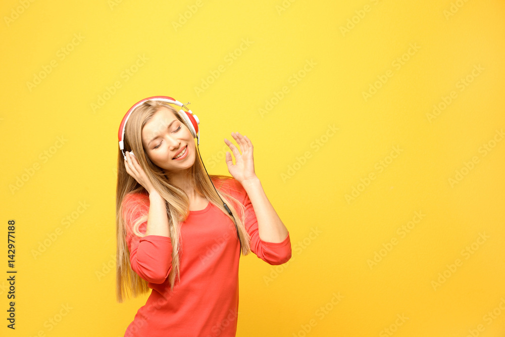 Beautiful young woman listening to music on color background