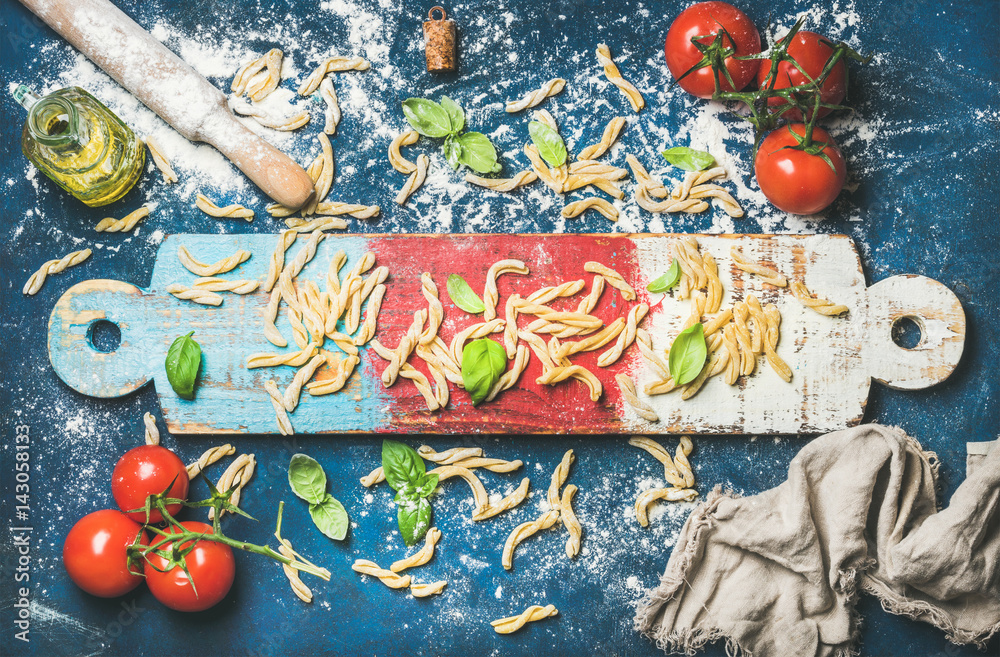 Ingredients for cooking Italian dinner. Fresh pasta casarecce, cherry-tomatoes, basil leaves and bot