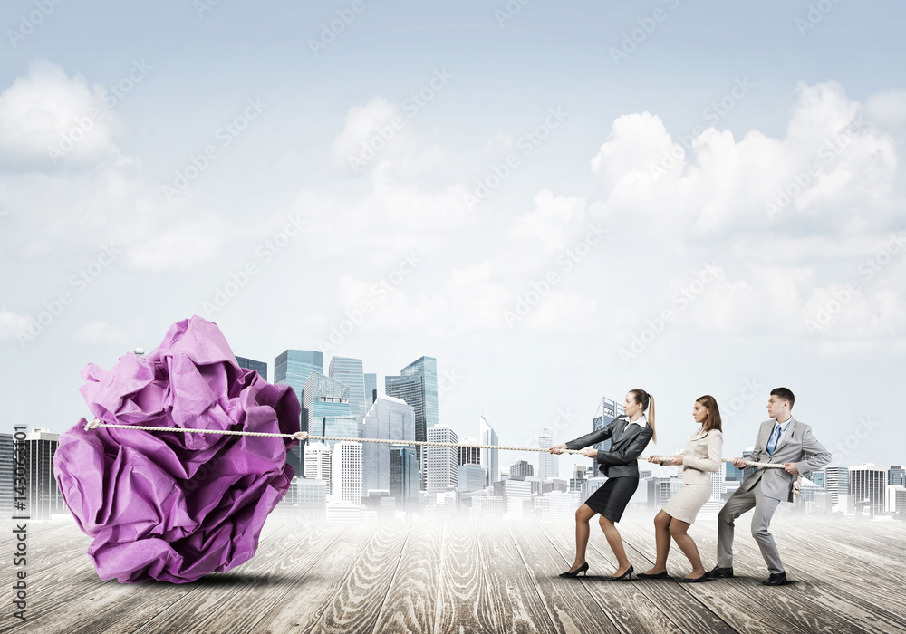 Young business people outdoors and huge paper ball as symbol of creativity