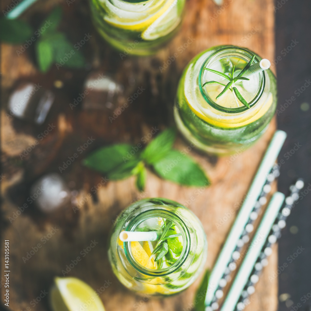 Citrus fruit and herbs infused sassi water for detox, healthy eating in bottles on wooden board over