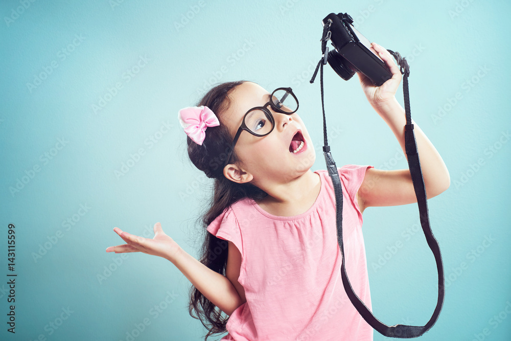 Little asian cute girl selfie with retro camera .  Vintage mint green wall background.