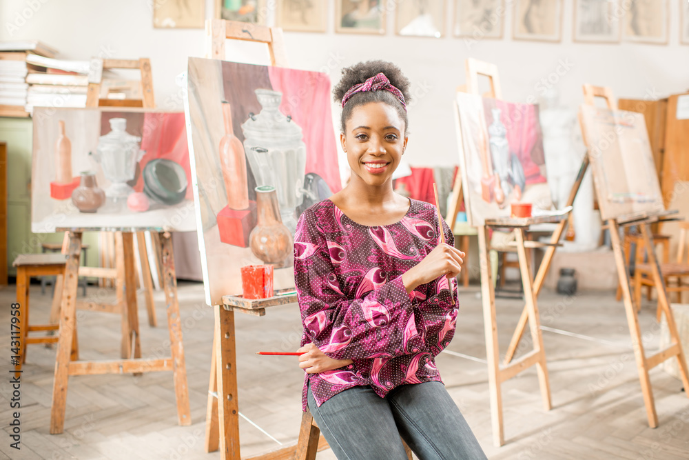 Portrait of a young african student sitting with still life painting at the studio