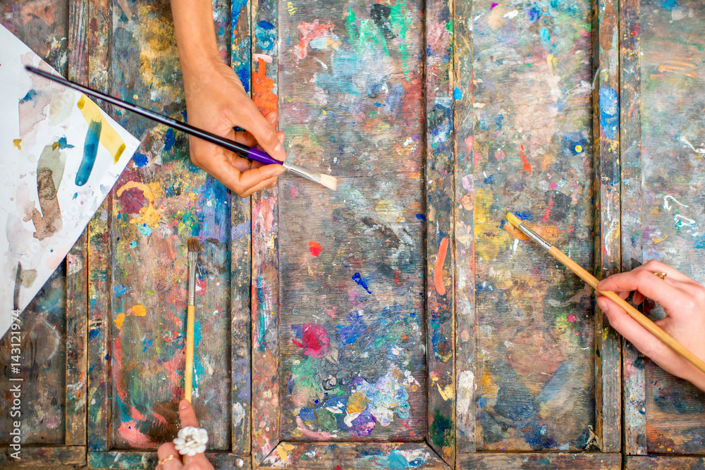 Hands mixing paints with brushes on the palette