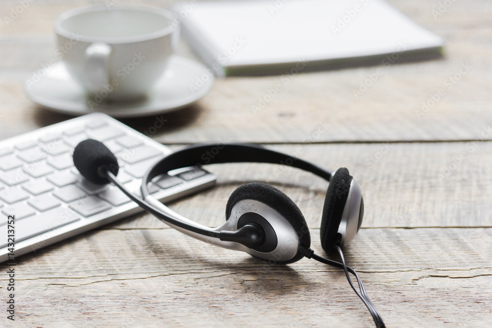 Office desk with headset and keyboard wooden background