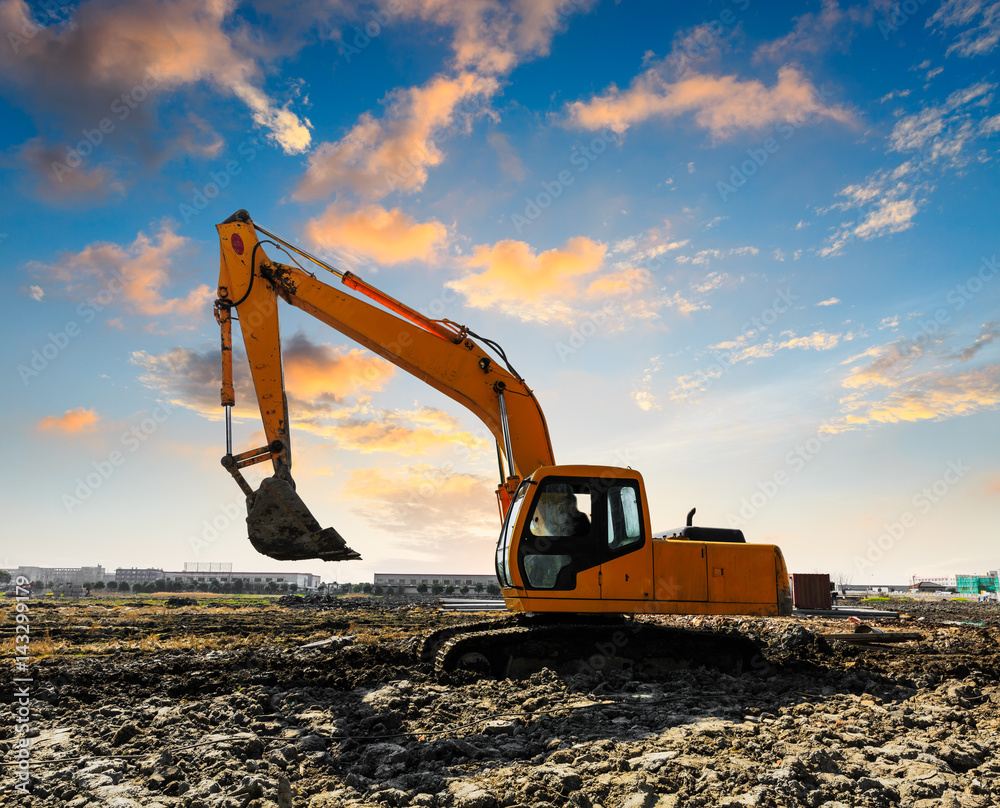 excavator in construction site on sunset sky background