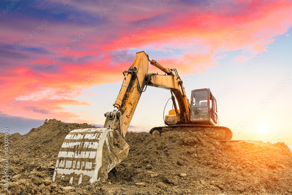 excavator in construction site on sunset sky background