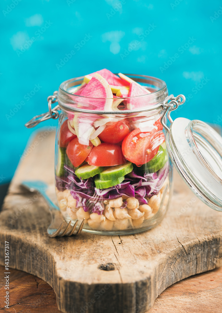 Healthy take-away lunch jar. Vegetable and chickpea sprout vegan salad in glass jar on wooden board,